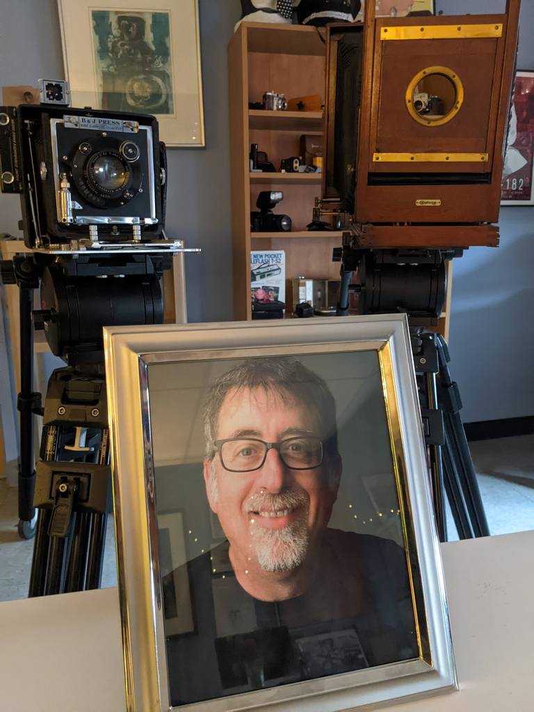 Framed photo of Kevin Salemme flanked by antique cameras.